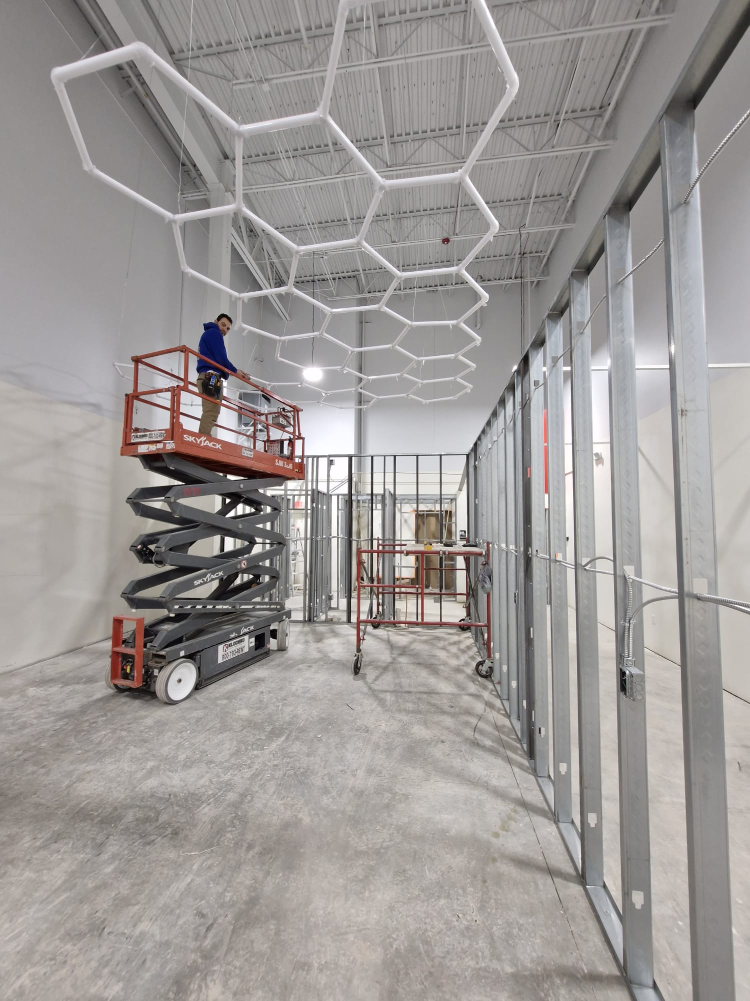 Electrician Installing Modern LED Hexagon Ceiling Lights in Commercial Construction Site